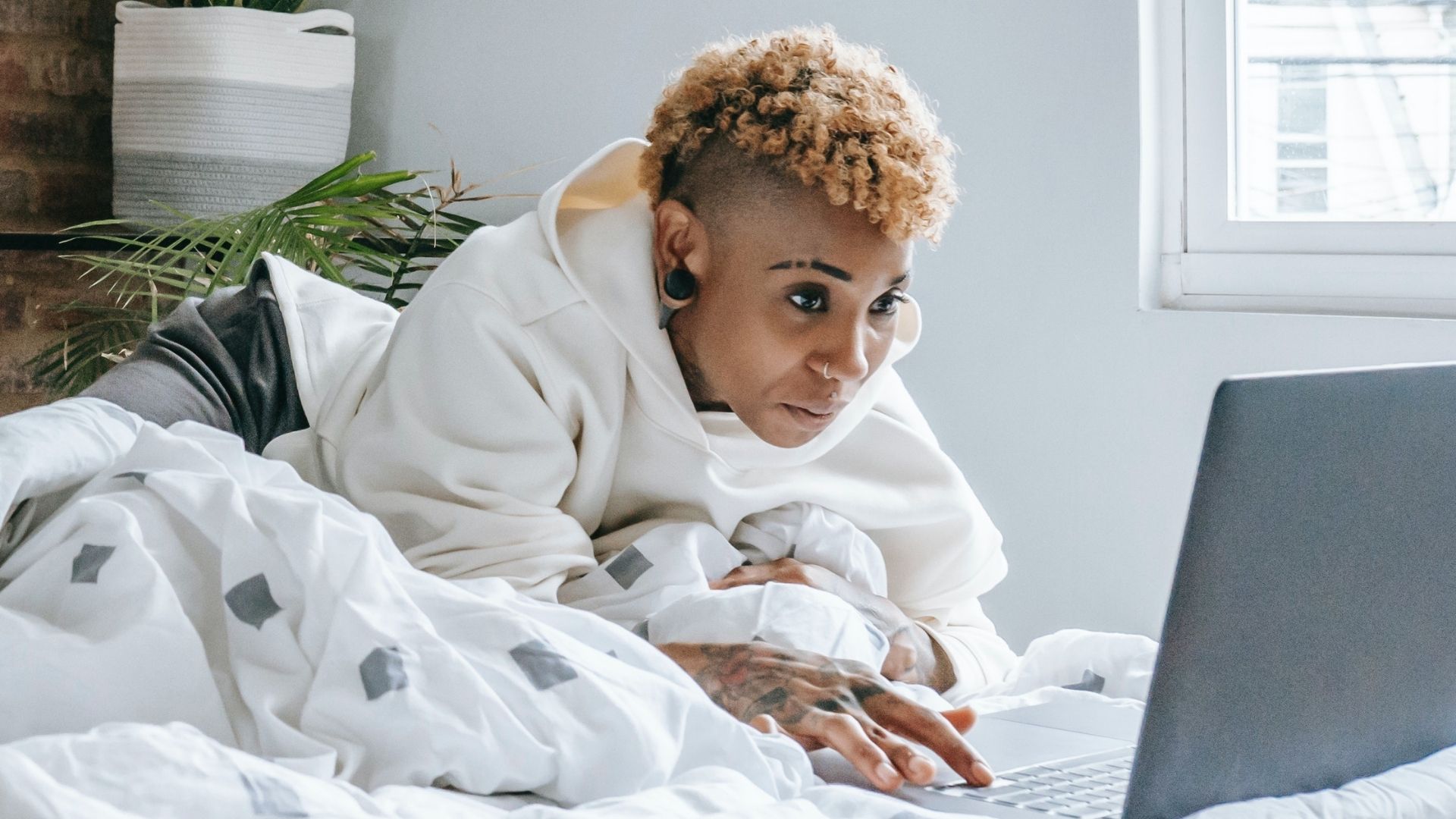 Jeune femme surfant sur internet dans son lit