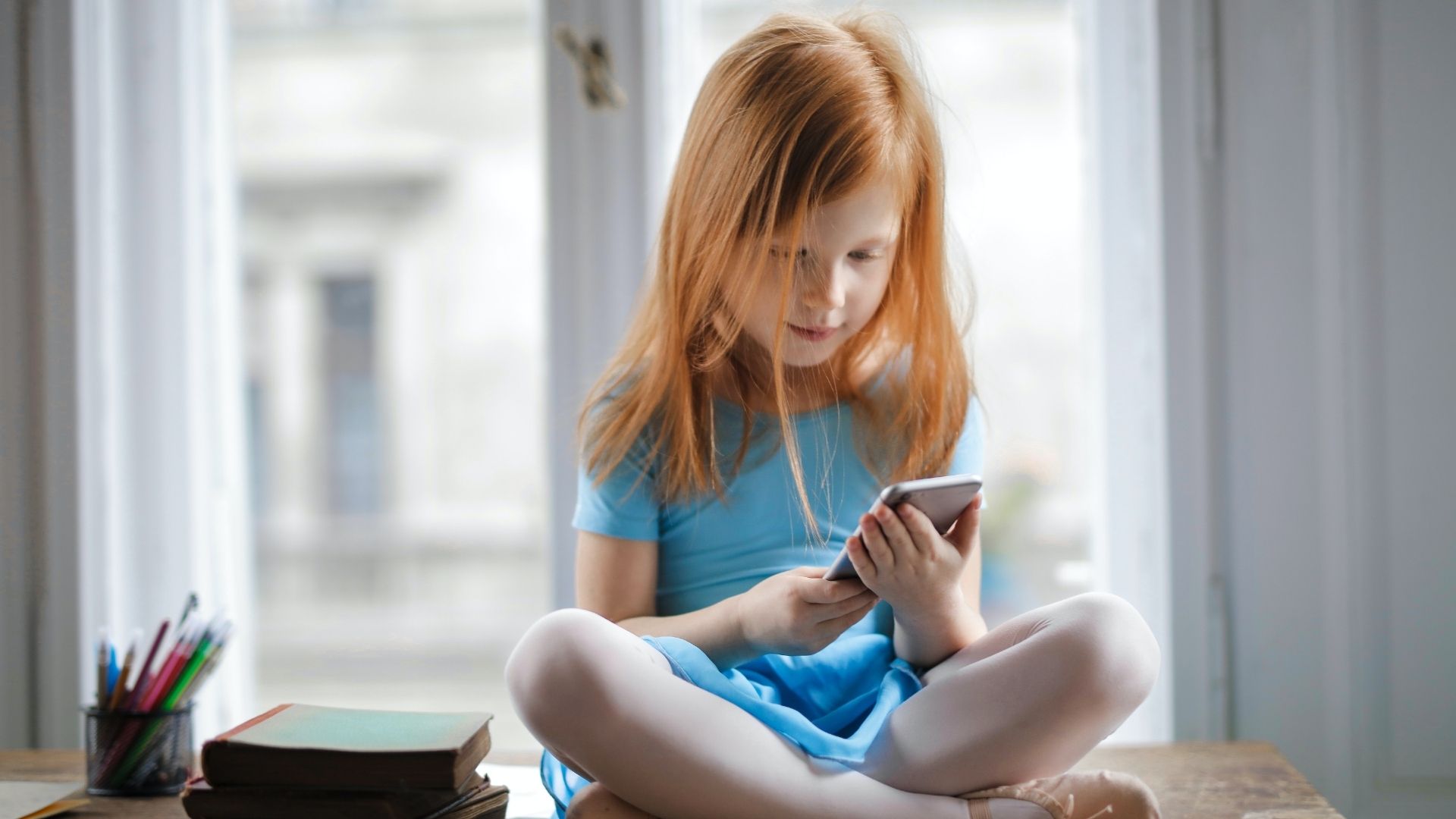 Enfant assise sur une table, un smartphone à la main